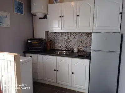 a kitchen with white cabinets and a white refrigerator at Chaleureux studio en bord de mer in Port-la-Nouvelle