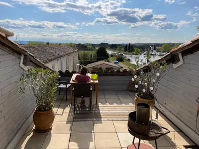 a woman sitting at a table on a balcony at Große Ferienwohnung am Canal du MIDI mit Dachterrrasse in Homps