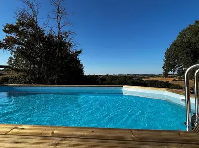 a large swimming pool with blue water at Gite à la ferme avec jacuzzi et piscine chauffée in Saint-Félix-de-Tournegat
