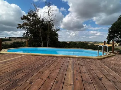 a swimming pool on a deck with a wooden floor at Gite à la ferme avec jacuzzi et piscine chauffée in Saint-Félix-de-Tournegat