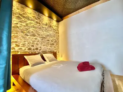 a bedroom with a white bed with a red hat on it at La Maison des Templiers ~ Ostal Médiéval ~ Logis enchantés in Carcassonne