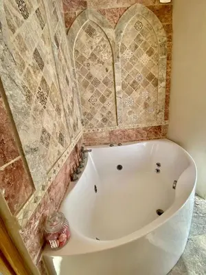 a bath tub in a bathroom with tiles on the wall at La Maison des Templiers ~ Ostal Médiéval ~ Logis enchantés in Carcassonne