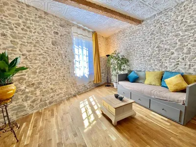 a living room with a couch and a stone wall at La Maison des Templiers ~ Ostal Médiéval ~ Logis enchantés in Carcassonne