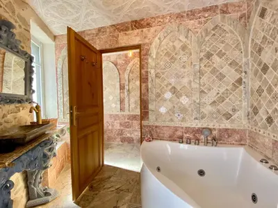 a bath tub in a bathroom with a tile wall at La Maison des Templiers ~ Ostal Médiéval ~ Logis enchantés in Carcassonne