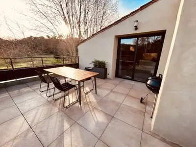 a patio with a table and chairs and a grill at Gites entre 2 rives in Montolieu