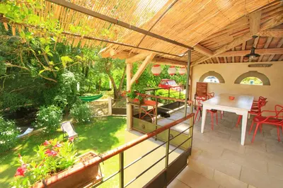 a patio with a table and chairs and a wooden roof at Gites entre 2 rives in Montolieu