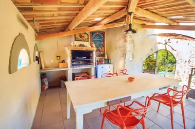 a kitchen with a wooden table and red chairs at Gites entre 2 rives in Montolieu