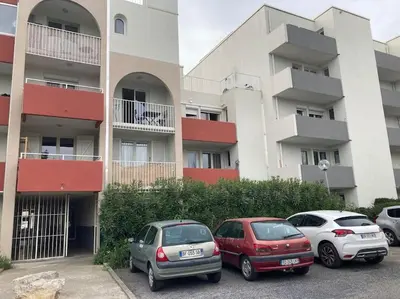 three cars parked in a parking lot in front of a building at Narbonne centre T2 avec jardinet et parking in Narbonne