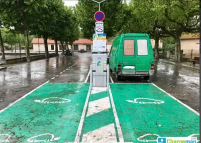 a green parking lot with a van parked on a street at Maison atypique dans circulade in Bram