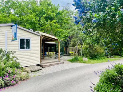a small white building with a porch and trees at Flower Camping La Pibola in Camon