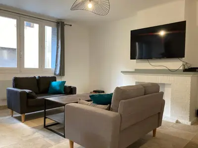 a living room with a couch and a tv on the wall at CARC'APPART Appartements à Carcassonne in Carcassonne