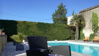 a swimming pool with chairs next to a hedge at Charme au cœur des vignes in Malras