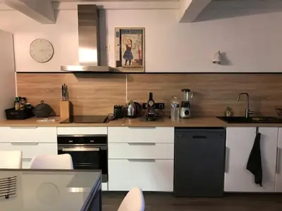 a kitchen with white cabinets and a black appliance at DOMAINE LA MASQUIERETTE in Villepinte