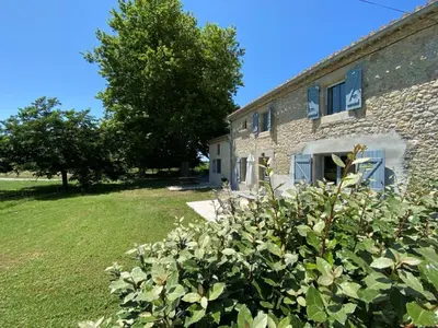 a stone house with a bush in front of it at DOMAINE LA MASQUIERETTE in Villepinte