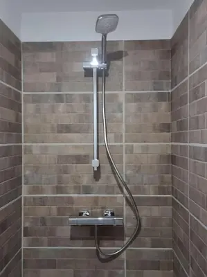 a shower with a hose in a tiled bathroom at maison des vendangeurs in Villarzel-Cabardès