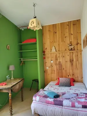 a bedroom with a bed and a wooden wall at Le sapin rouge - Restaurant - bar - chambres d'hôtes in Artigues