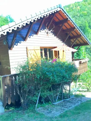 a small white house with an umbrella and some bushes at Chalet de charme in Montfort-sur-Boulzane