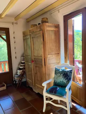 a room with a chair and a wooden cabinet at Chalet de charme in Montfort-sur-Boulzane