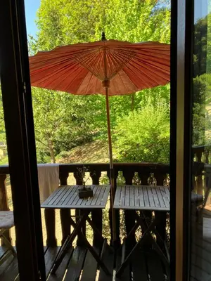a table with an umbrella on a porch at Chalet de charme in Montfort-sur-Boulzane