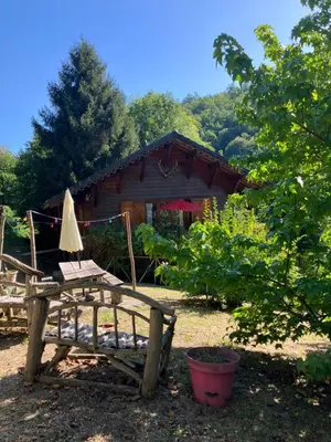 a bench and an umbrella in front of a cabin at Chalet de charme in Montfort-sur-Boulzane