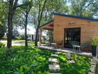 a small building with chairs in a yard at Camping La Capelle in Saint-Martin-Lalande