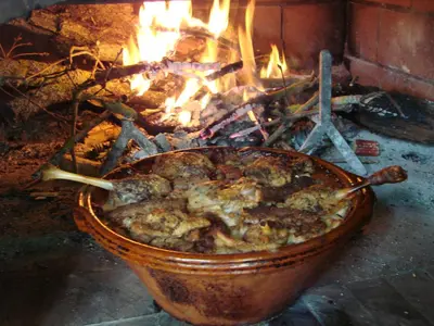 a pot of food in front of a fire at Camping La Capelle in Saint-Martin-Lalande