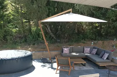 a patio with a couch and an umbrella at Magnifique villa avec piscine, jacuzzi et billard in Limoux