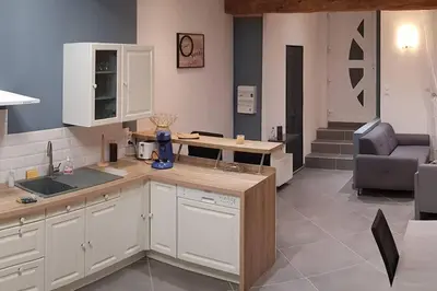 a kitchen with white cabinets and a table and a chair at Gîte avec Piscine Proche de Carcassonne in Couffoulens