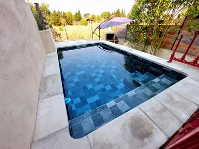 a swimming pool with blue tiles on the ground at Gîte avec Piscine Proche de Carcassonne in Couffoulens
