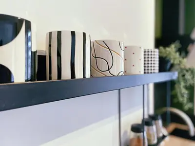 a shelf with cups sitting on top of it at L'alcôve - T2 Calme, Terrasse & Parking privé in Castres