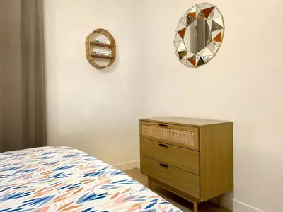 a bedroom with a bed and a dresser and a mirror at L'alcôve - T2 Calme, Terrasse & Parking privé in Castres