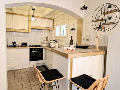 a kitchen with white cabinets and a counter with stools at Maison Richelieu in Bram