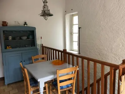 a dining room table with chairs and a blue cabinet at La Cerisaie - Chambres d'hôtes & gites in Riols