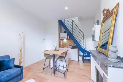 a kitchen and living room with a table and a blue couch at Romantique Duplex au pied de la cité in Carcassonne