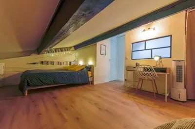 a bedroom with a bed and a desk and a window at Romantique Duplex au pied de la cité in Carcassonne