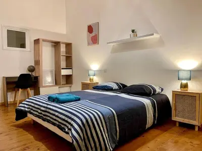 a bedroom with a large bed with blue pillows on it at Appartement confort - Carcassonne centre in Carcassonne