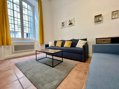 a living room with a blue couch and a table at Appartement confort - Carcassonne centre in Carcassonne