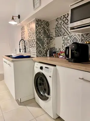 a kitchen with a washing machine under a counter at Appartement confort - Carcassonne centre in Carcassonne