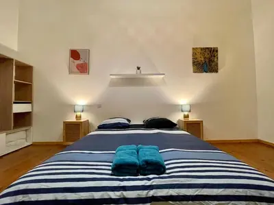 a bedroom with a large bed with two blue pillows at Appartement confort - Carcassonne centre in Carcassonne