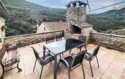 a table and chairs on a patio with a stone chimney at Cozy Home In Olargues With Kitchen in Olargues