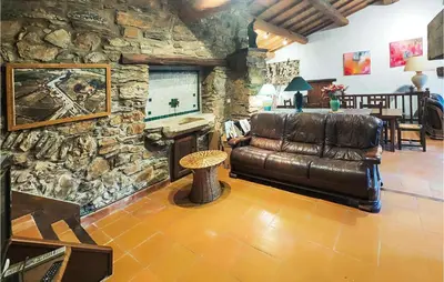 a living room with a leather couch and a stone wall at Cozy Home In Olargues With Kitchen in Olargues