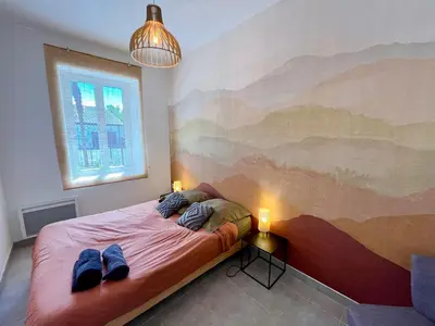 a bedroom with a bed with a painting on the wall at Le Riquet - jardin privé, clim, RDC in Castelnaudary
