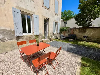 a red table and chairs in front of a house at Le Riquet - jardin privé, clim, RDC in Castelnaudary