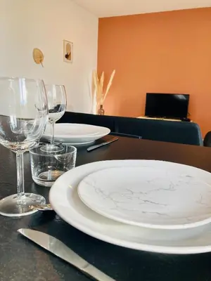 a table with two white plates and wine glasses at Le Riquet - jardin privé, clim, RDC in Castelnaudary