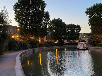a river with lights reflecting in the water at night at Dupleix au Fil du Canal in Narbonne