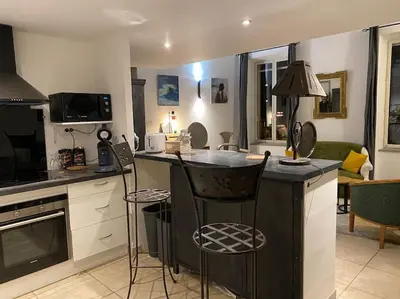 a kitchen with a counter and chairs in a room at Dupleix au Fil du Canal in Narbonne