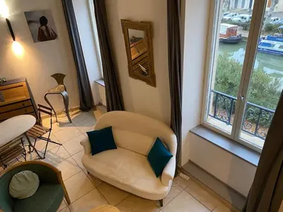 a living room with a chair and a window at Dupleix au Fil du Canal in Narbonne