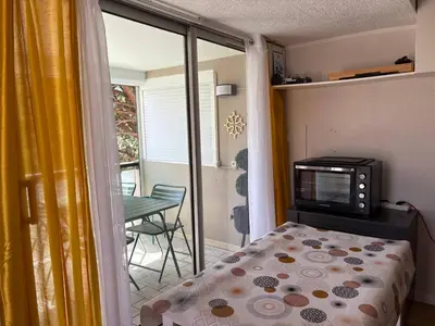 a bedroom with a bed and a television and a balcony at Le zéphyr in Gruissan