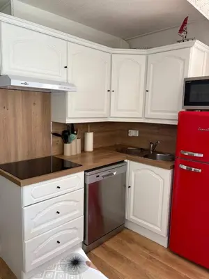 a kitchen with white cabinets and a red refrigerator at Le zéphyr in Gruissan