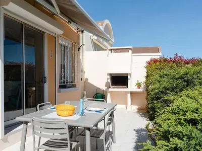 a table and chairs on the patio of a house at Pavillon lumineux avec terrasse, à 1 km de la plage – 2 pièces, 1 chambre, barbecue, Wi-Fi - FR-1-409A-3 in Gruissan